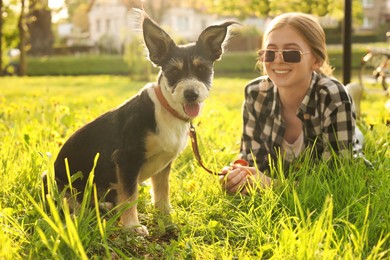 Photo of Teenage girl with her cute dog resting on green grass in park
