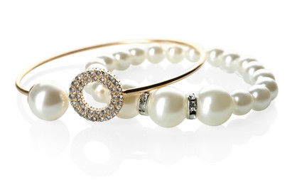 Elegant pearl and golden bracelets on white background