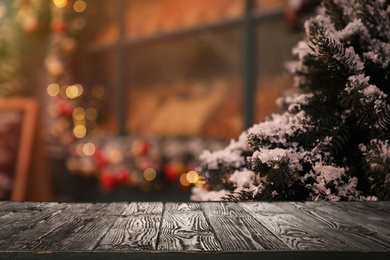 Empty wooden surface and fir branches covered with snow on blurred background. Christmas time