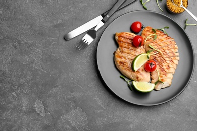 Tasty grilled chicken fillets served on grey table, flat lay. Space for text