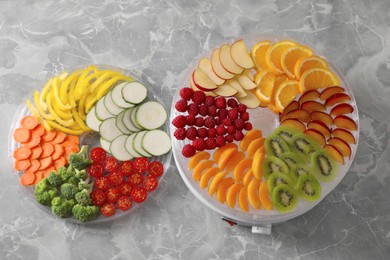 Cut fruits, vegetables and dehydrator machine on grey marble table, flat lay