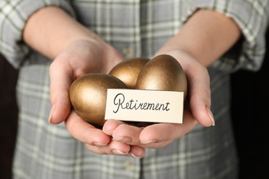 Woman holding golden eggs and card with word Retirement, closeup. Pension concept