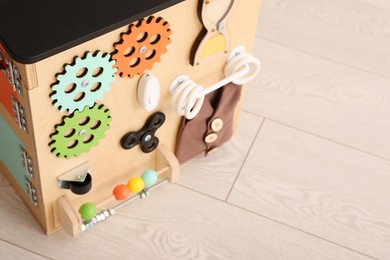 Busy board house on floor indoors, closeup view space for text. Baby sensory toy
