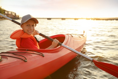 Happy boy kayaking on river. Summer camp activity