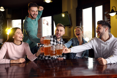 Group of friends celebrating victory of favorite football team in sport bar