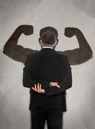 Businessman and shadow of strong muscular man in front of him on grey wall. Concept of inner strength