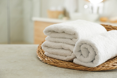 Wicker tray with clean towels on table in bathroom