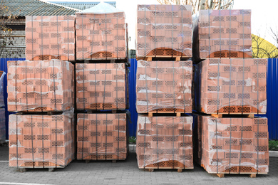 Pallets with red bricks outdoors. Building materials wholesale