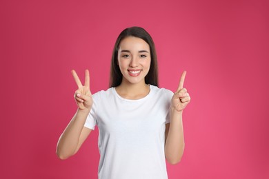 Woman showing number three with her hands on pink background