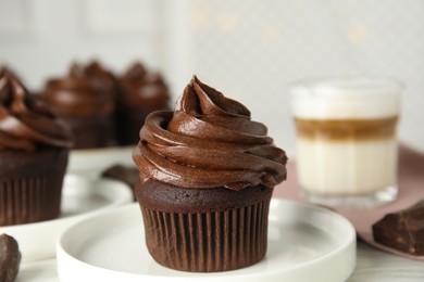Plate with delicious chocolate cupcake on white table