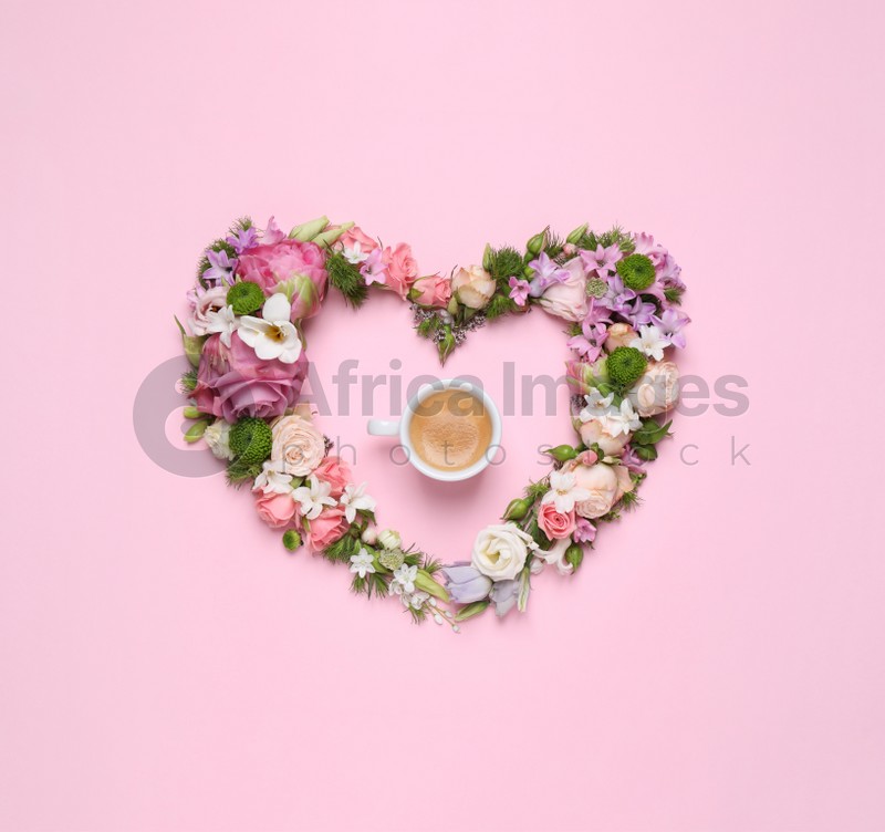 Beautiful heart made of different flowers and coffee on pink background, flat lay