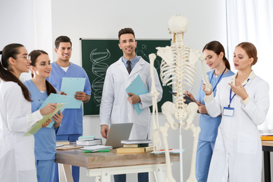 Medical students studying human skeleton anatomy in classroom
