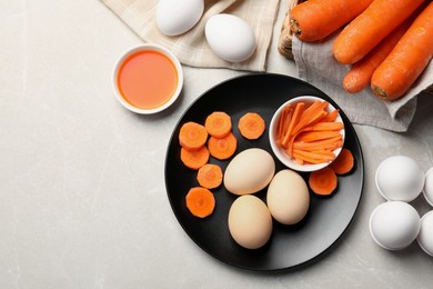 Photo of Naturally painted Easter eggs on light grey table, flat lay with space for text. Carrot used for coloring