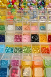Photo of Organizers with variety of colorful beads on yellow background, closeup