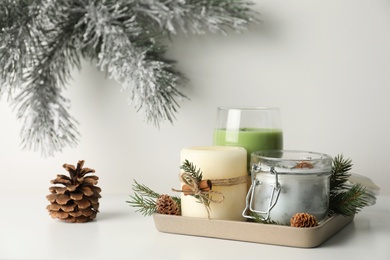 Composition with scented conifer candles and Christmas decor on white table