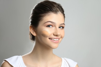 Beautiful girl on light grey background. Using concealer and foundation for face contouring