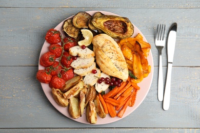 Photo of Tasty cooked chicken fillet and vegetables served on grey wooden table, flat lay. Healthy meals from air fryer