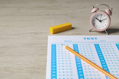 Photo of Answer sheet, pencil and alarm clock on wooden table, space for text. Student passing exam