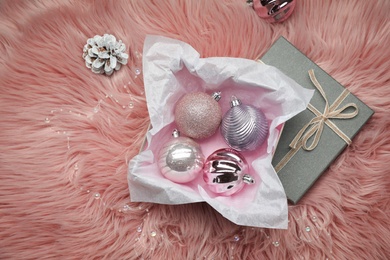 Beautiful Christmas baubles in box on pink faux fur, flat lay