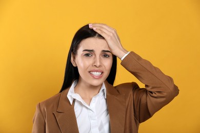 Woman suffering from migraine on yellow background
