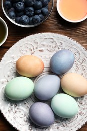 Photo of Naturally painted Easter eggs on wooden table, flat lay. Blueberries and onion used for coloring