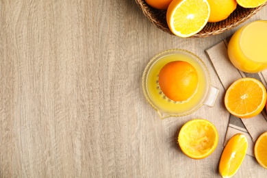 Squeezer, fresh oranges and juice on wooden table, flat lay. Space for text