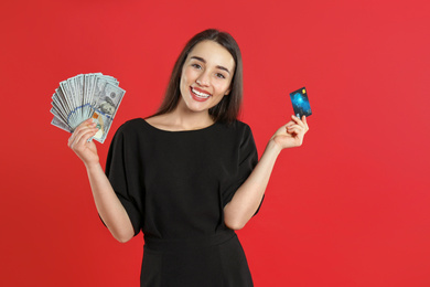 Young woman with money and credit card on crimson background