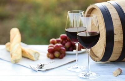 Photo of Composition with barrel of wine and products on table outdoors, closeup