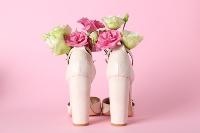 Stylish women's high heeled shoes with beautiful flowers on pink background