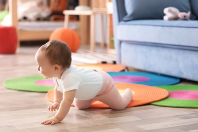 Photo of Cute baby crawling on floor in living room