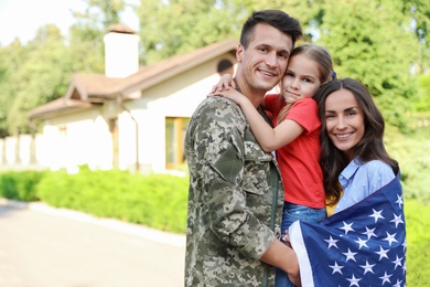 Man in military uniform and his family with American flag outdoors