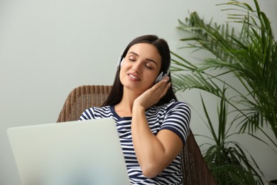Young woman listening to music while working on laptop at home