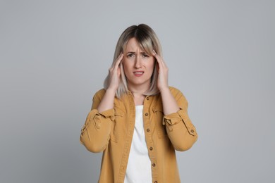 Woman suffering from headache on light grey background