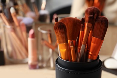Photo of Set of professional brushes and makeup products near mirror, closeup. Space for text