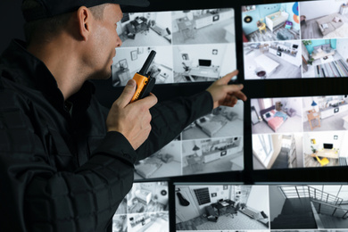 Security guard with portable transmitter monitoring modern CCTV cameras indoors