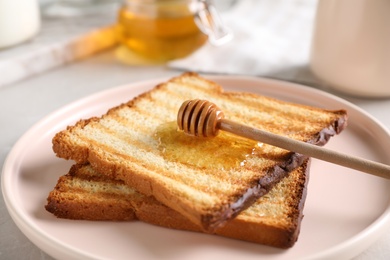 Tasty toasts with honey served on table, closeup
