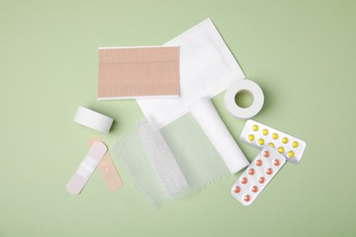 Photo of White bandage and medical supplies on light green background, flat lay