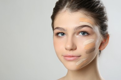 Photo of Beautiful girl on light grey background. Using concealer and foundation for face contouring