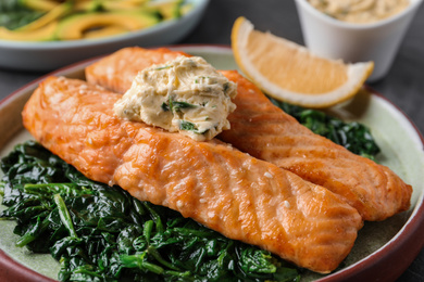 Tasty salmon with spinach on plate, closeup