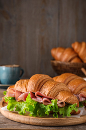 Tasty croissant sandwiches with ham on wooden table