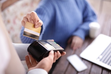 Woman with credit card using payment terminal at restaurant, closeup