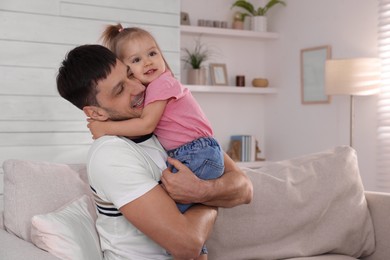 Father with his cute little daughter on sofa at home