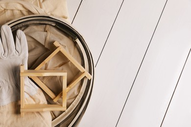 Photo of Honeycomb frames and beekeeping tools on white wooden table, flat lay. Space for text