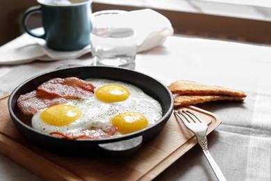 Tasty fried eggs with bacon and toasts on table, space for text