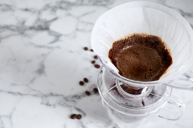 Brewing tasty coffee using drip filter on white marble table, closeup. Space for text