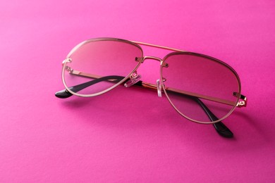 New stylish sunglasses on pink background, closeup. Fashionable accessory