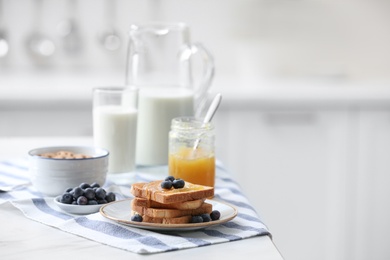 Toasted bread with jam and blueberries on white marble table in kitchen, space for text