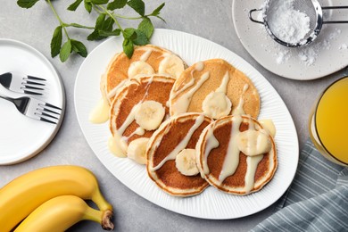 Tasty pancakes with sliced banana served on grey table, flat lay
