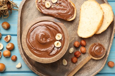 Flat lay composition with tasty chocolate paste and hazelnuts on light blue wooden table