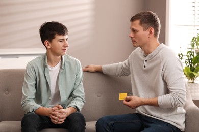 Father talking with his teenage son about contraception at home. Sex education concept